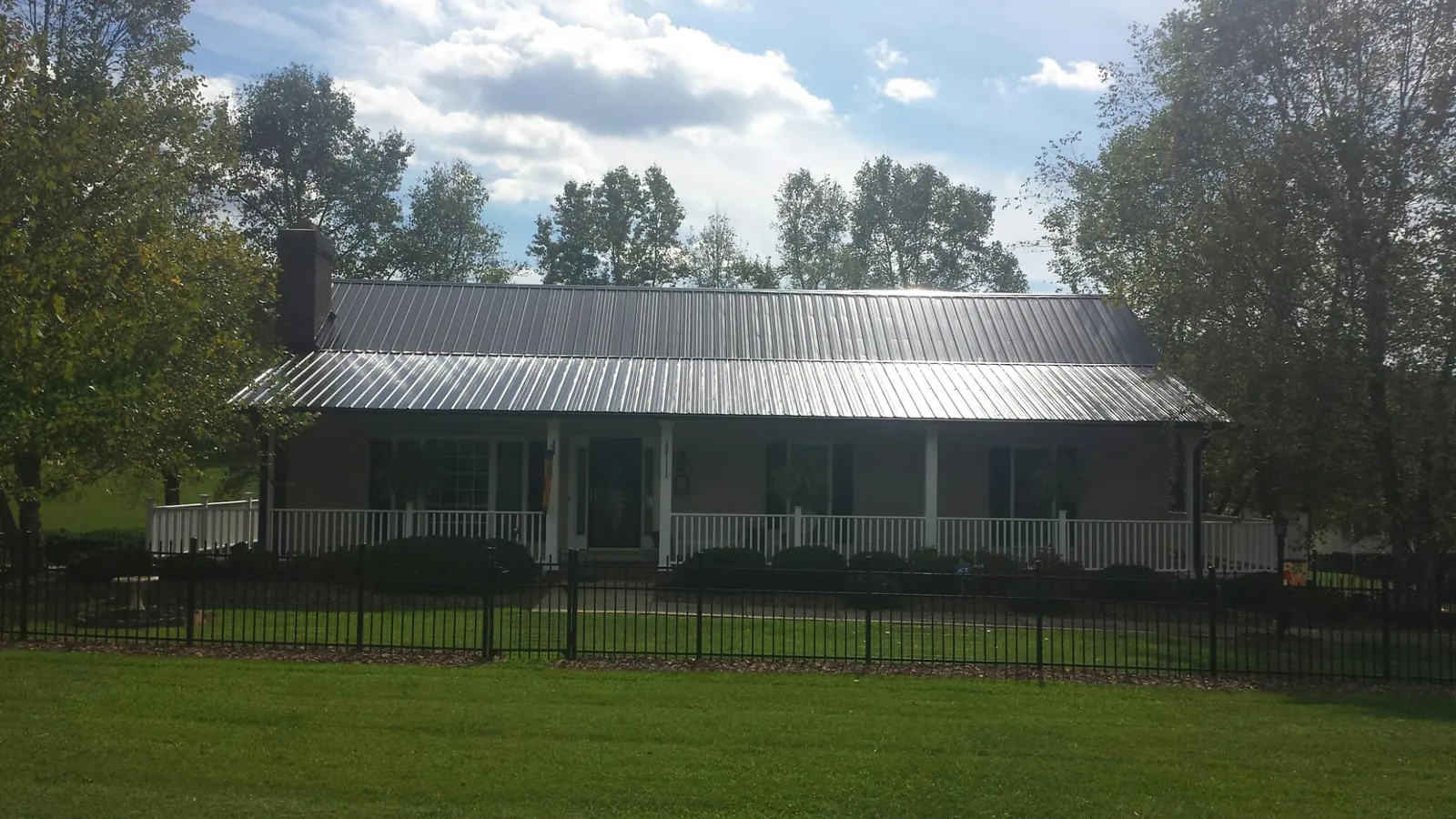 Gray metal roof on a brick ranch with a full width front porch — Gutter Guard Installation work by our crew in Ray City