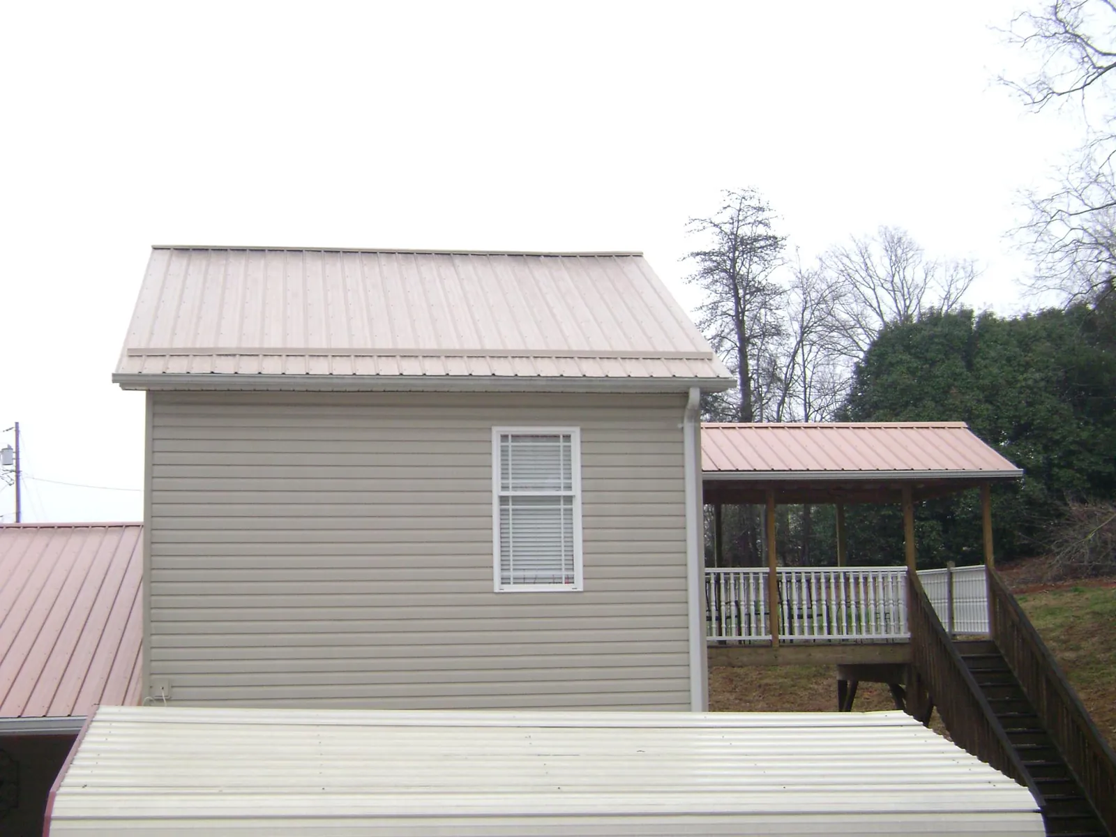 Tan metal roofs on a two story addition and attached porch, from a Roof Replacement job in Ray City